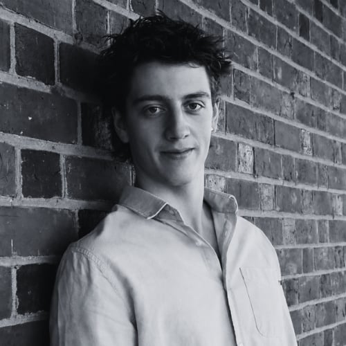 Black and white portrait of James Woods, founder of Woods Media Promotions, standing against a brick wall