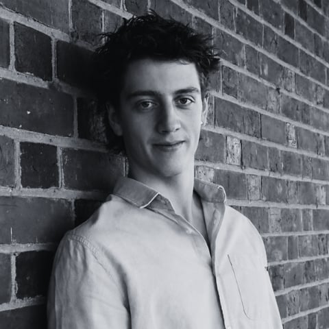 Black and white portrait of James Woods, founder of Woods Media Promotions, standing against a brick wall
